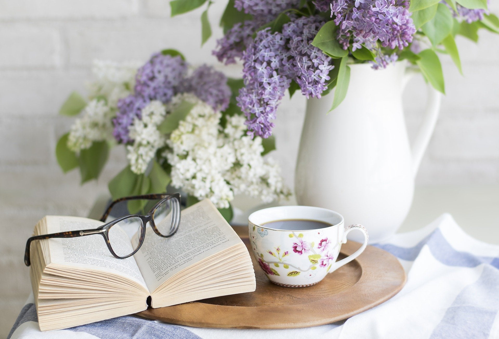 a cup of coffee and a book on a table with flowers