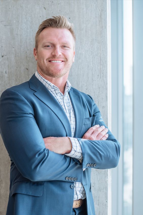 Tyler Clutts smiling and wearing a blue suit